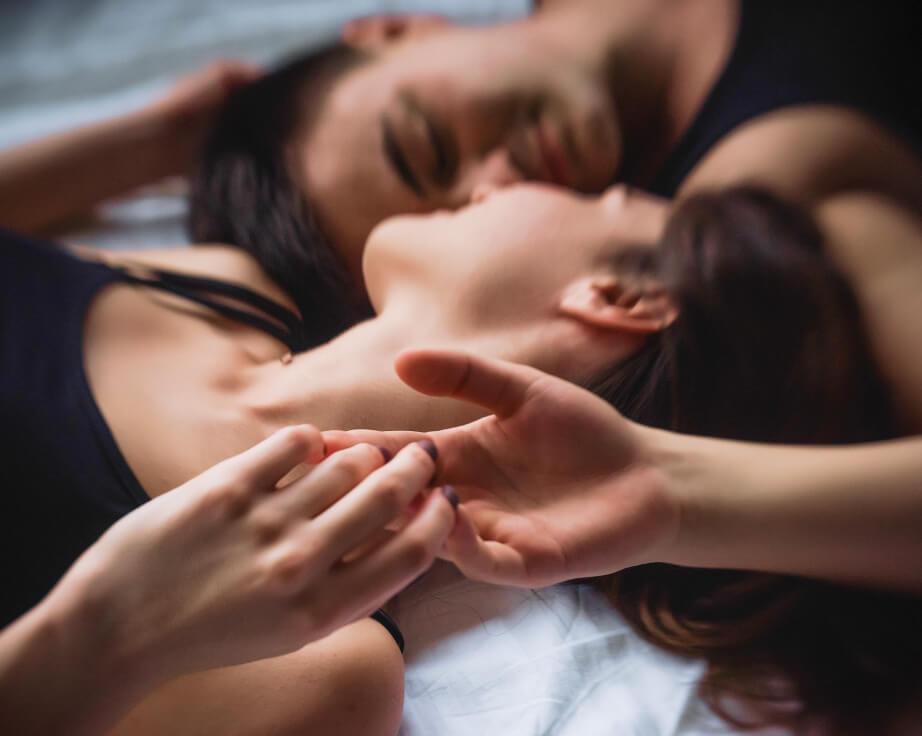 Couple laying in bed touching hands