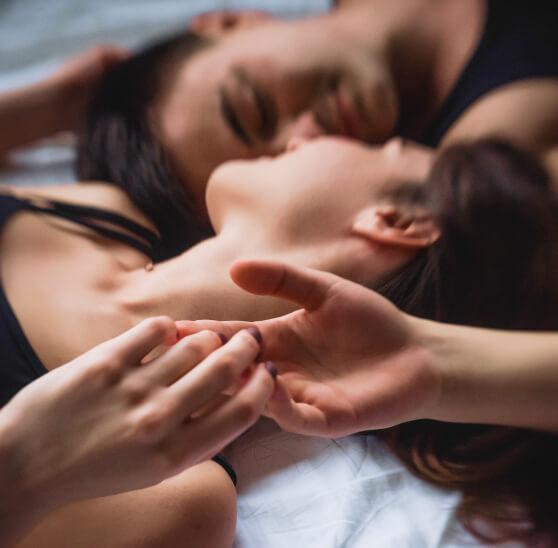 Couple laying in bed touching hands